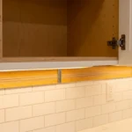 Storm-rated cabinet installation in a Florida kitchen showing plywood mounting rail and structural fasteners